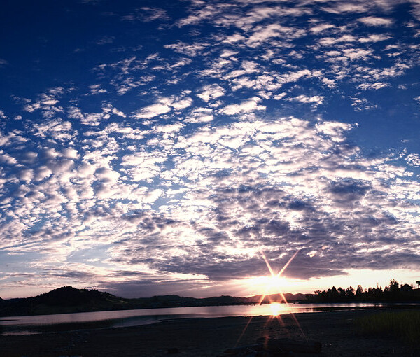 Sonnenuntergang am Sihlseeli mit Wolken und dunkler Silhouette im Hintergrund.
