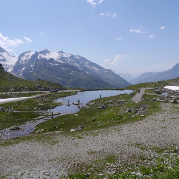 Steinsee in den Schweizer Alpen mit schneebedeckten Bergen und blauem Himmel.