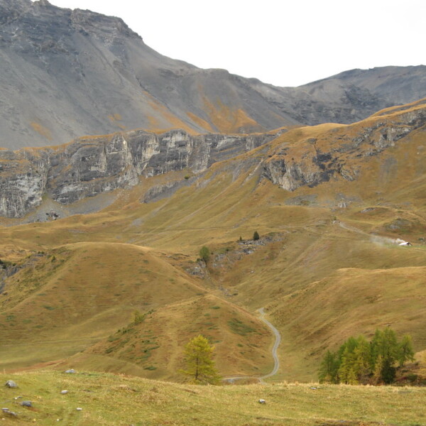 Herbstliche Landschaft in Tièche mit Wasserfall und Bergen.