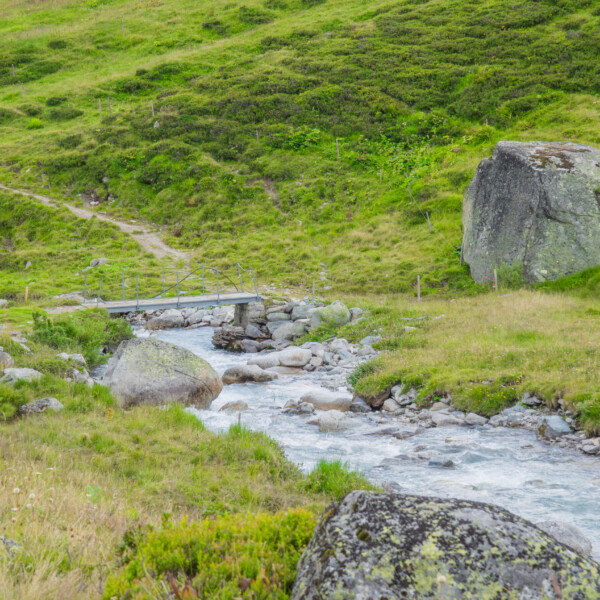 Brücke über einen Bach in Tiefenbach, grüne Landschaft mit Felsen.