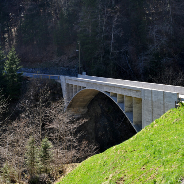Betonbogenbrücke bei Traubach, eingebettet in grüne Hügel und dunklen Wald.