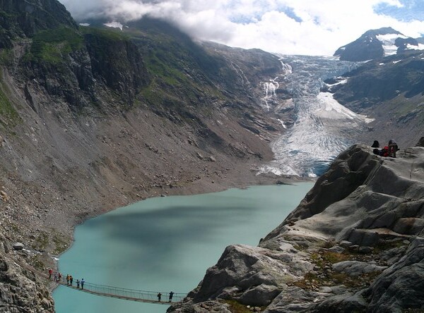 Triftsee: Hängebrücke über türkisfarbenen See mit Gletscher im Hintergrund.