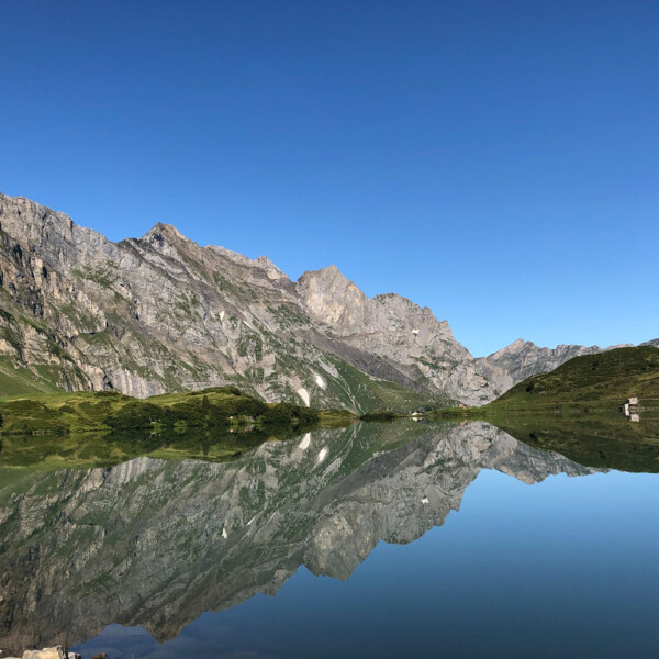Spiegelung der Berge im Trübsee, Schweiz. Ruhige Wasseroberfläche.