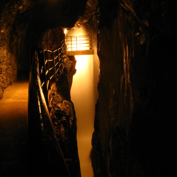 Trümmelbachfälle: Beleuchteter Felsdurchbruch mit Steg in der Schlucht.