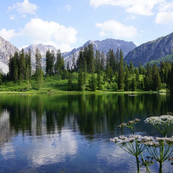 Untersee Arosa: Ruhiger Bergsee mit Spiegelung von Bäumen und Bergen im Wasser.