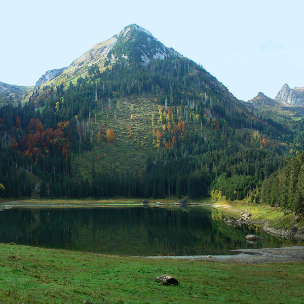 Voralpsee: Idyllischer Bergsee mit bewaldeten Hängen und Herbstfarben.