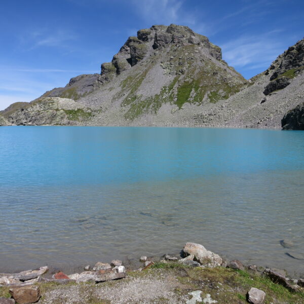 Türkisblauer Wildsee in den Bergen unter blauem Himmel.