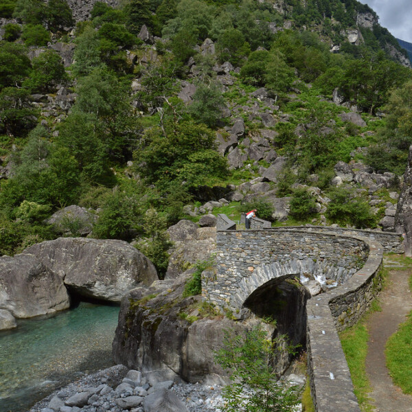 Steinbrücke in Bavona, Tessin, über einen klaren Fluss. Grüne Landschaft.
