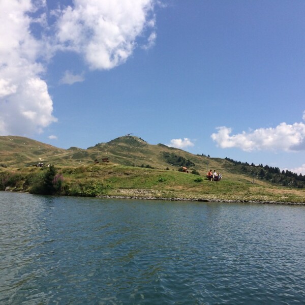 Bettmersee See mit grünen Hügeln und blauem Himmel.