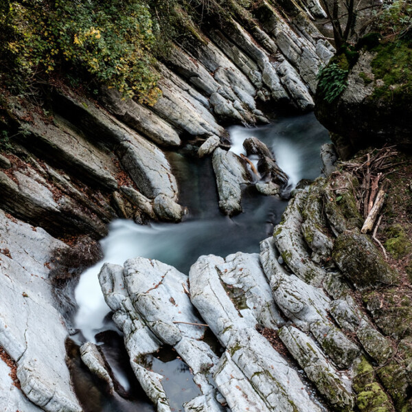 Fluss schlängelt sich durch die Breggia-Schlucht mit glatten, weißen Felsen und üppigem Grün.