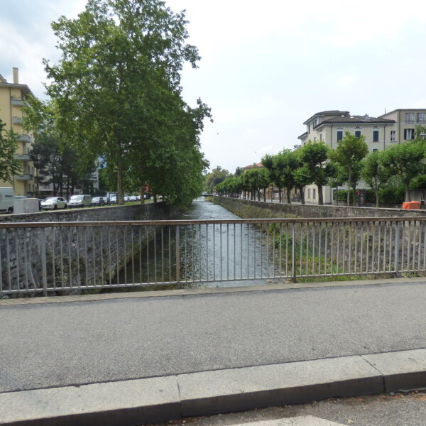 Cassarate Fluss in Lugano, Schweiz mit Brücke und Gebäuden.