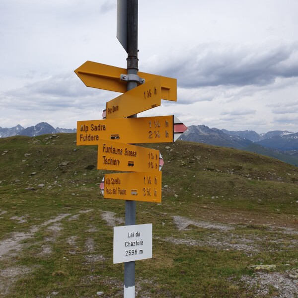 Wegweiser am Lai da Chazfora (2596 m) mit Zielen wie Alp Sadra, Fuldera, und Piz Dara.