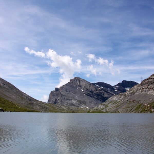 Daubensee: Ruhiger Bergsee mit Spiegelung der umliegenden Berge unter blauem Himmel.