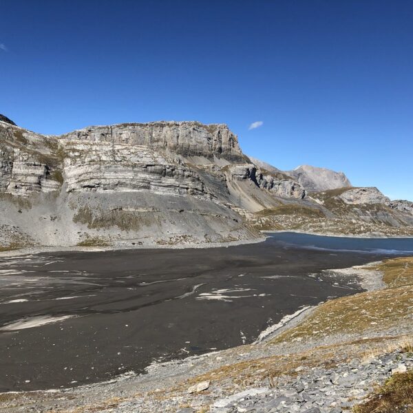 Daubensee: Bergsee in den Schweizer Alpen mit markanten Felsformationen und blauem Himmel.