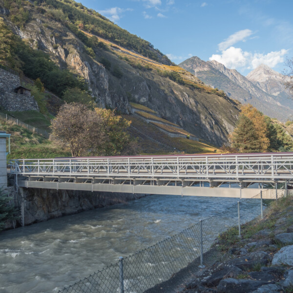 Drance: Brücke über den Fluss mit Bergen im Hintergrund.