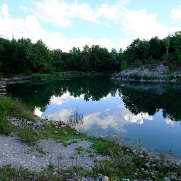 Der Étang des Bouvières, ein ruhiger See umgeben von Bäumen, spiegelt den Himmel wider.