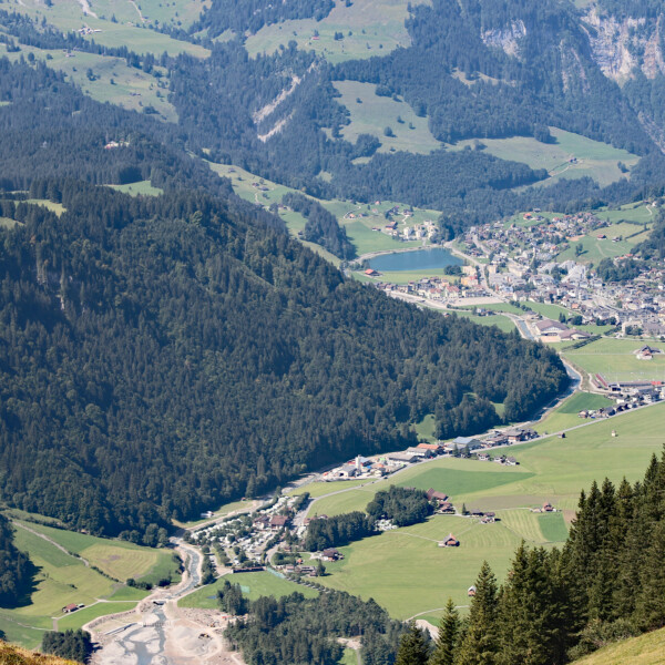 Eugenisee-Blick: Tal mit Wiesen, Wald, Häusern und See in den Schweizer Alpen.