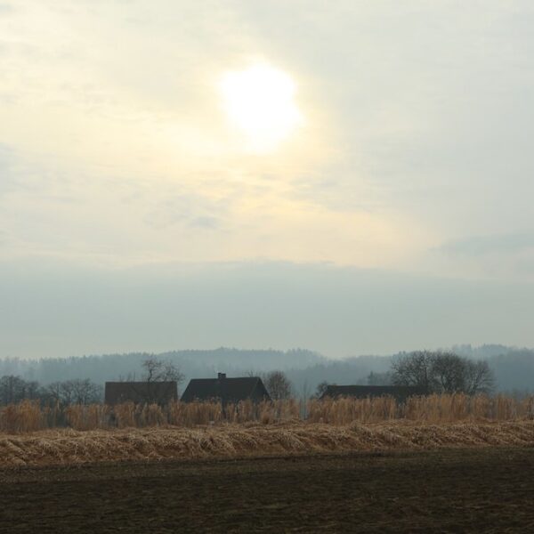 Flachsee Landschaft mit Feldern und Häusern unter bewölktem Himmel.