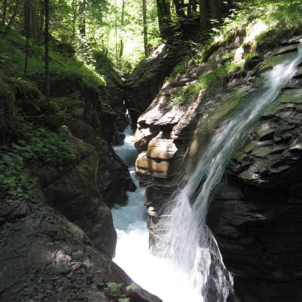 Wasserfall in der Flem-Schlucht, umgeben von üppigem Grün und Felsen.