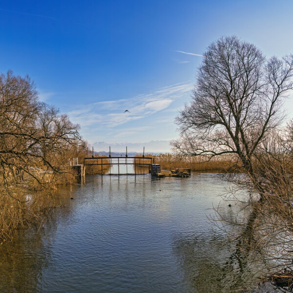 Glatt Zürich: Flusslandschaft mit Brücke unter blauem Himmel.