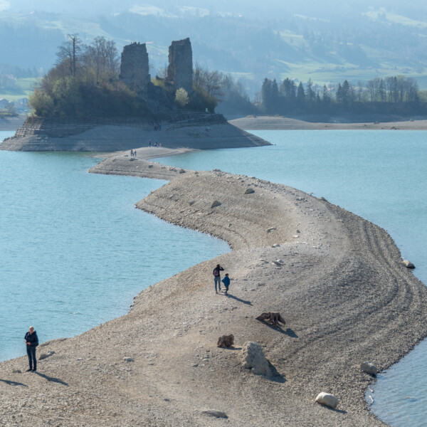 Sandbank zum Schloss Île d'Ogoz im Greyerzersee, Schweiz. Wanderer auf dem Weg.