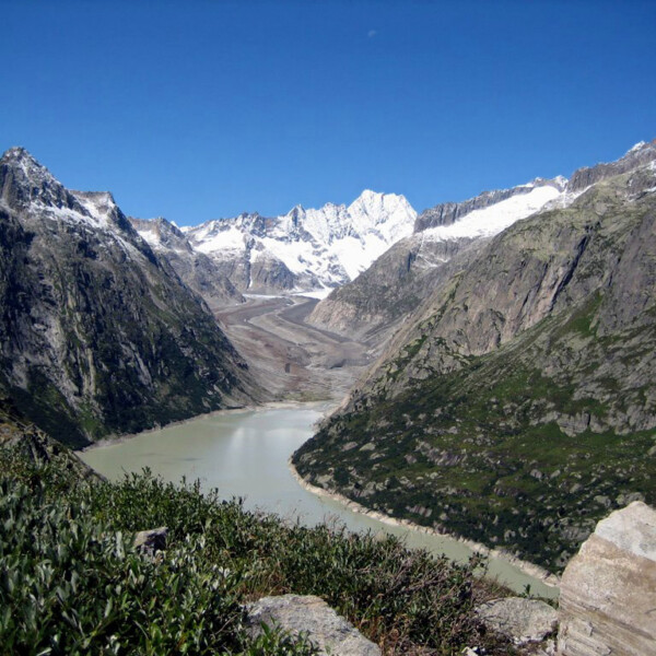Grimselsee-Panorama mit Gletscher, Bergen und blauem Himmel.