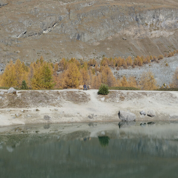 Grünsee Zermatt: Herbstliche Landschaft mit See, Bäumen und Bergen im Hintergrund.