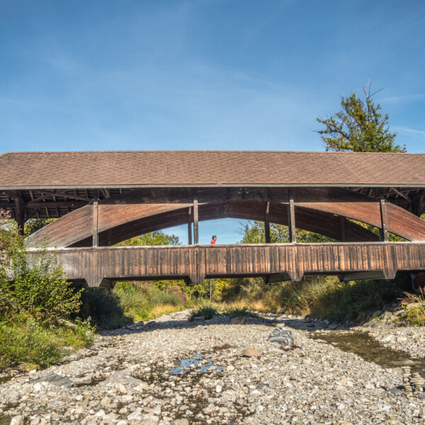 Gedeckte Holzbrücke über die Gürbe, Bern. Person überquert die Brücke.