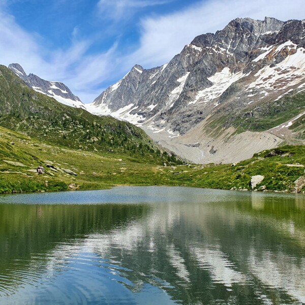 Guggisee: Bergsee mit Spiegelung der schneebedeckten Gipfel und grünen Hängen.