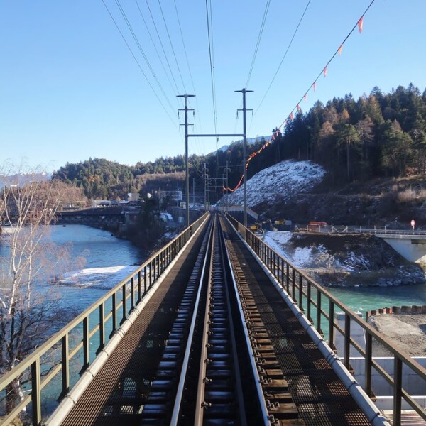 Eisenbahnbrücke über den Hinterrhein mit Blick auf Bäume und Berge