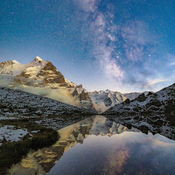 Sternenhimmel über dem Hornseeli mit Spiegelung der Berge im Wasser.