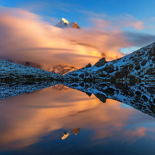 Hornseeli Spiegelung: Bergspitze ragt aus Wolken über einem ruhigen See.