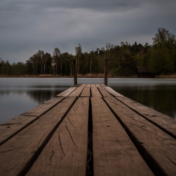 Holzsteg am Husemersee unter bewölktem Himmel