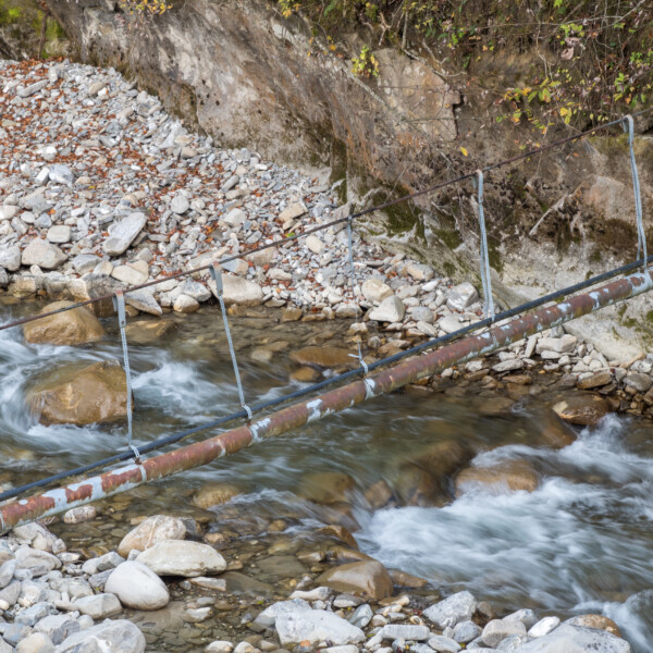 Alte Rohrbrücke über den Fluss Kalte Sense, umgeben von Felsen und Geröll.