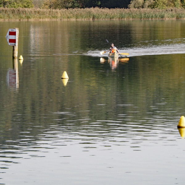 Kajakfahrer auf dem Klingnauer Stausee, umfährt Bojen und eine rot-weiße Markierung.
