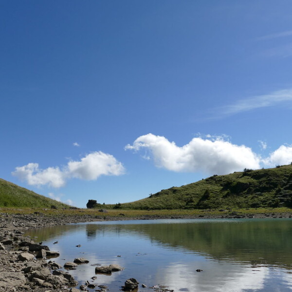 Lac de Chésery: Ruhiger Bergsee mit Spiegelung des blauen Himmels und der Wolken.