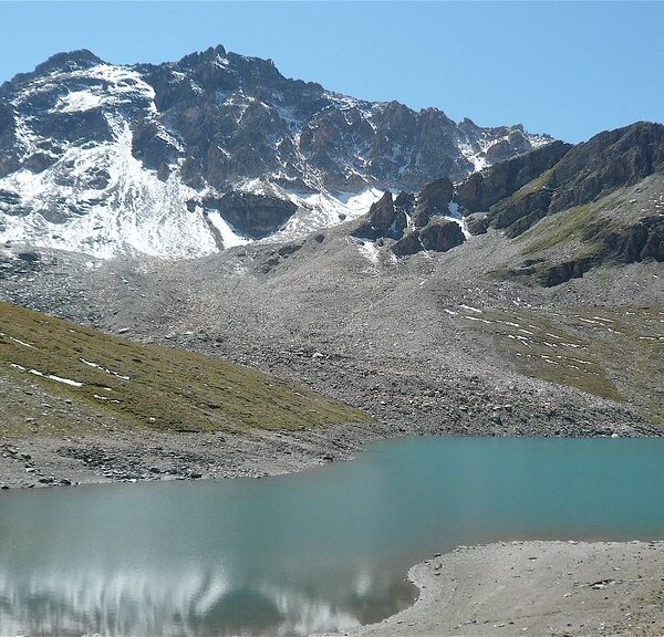 Lac de Lona: Bergsee mit schneebedeckten Gipfeln und klarer Spiegelung des Himmels.