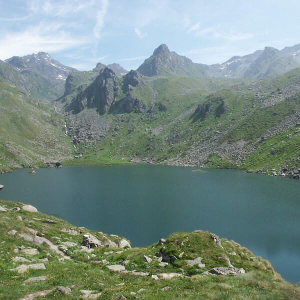Lac de Louvie: Bergsee eingebettet in grüne Alpenlandschaft mit felsigen Gipfeln.