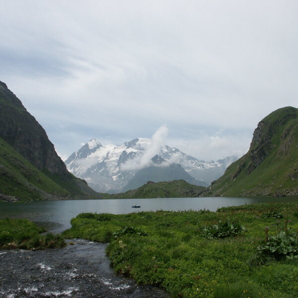 Lac de Louvie: Bergsee mit schneebedeckten Gipfeln und grünen Hängen in den Schweizer Alpen.