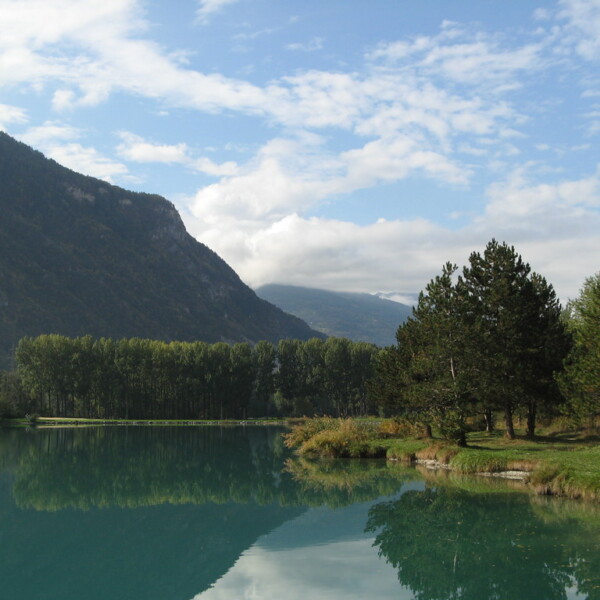 Spiegelung des Lac de la Brèche mit Bergen und Bäumen im ruhigen Wasser.