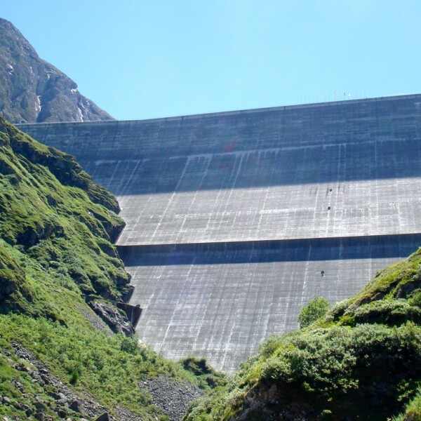 Lac des Dix Staumauer mit grünen Berghängen unter blauem Himmel.