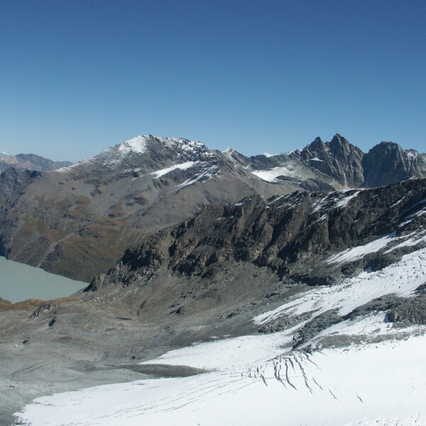 Lac des Dix: Berglandschaft mit See, Schnee und Felsen unter blauem Himmel.