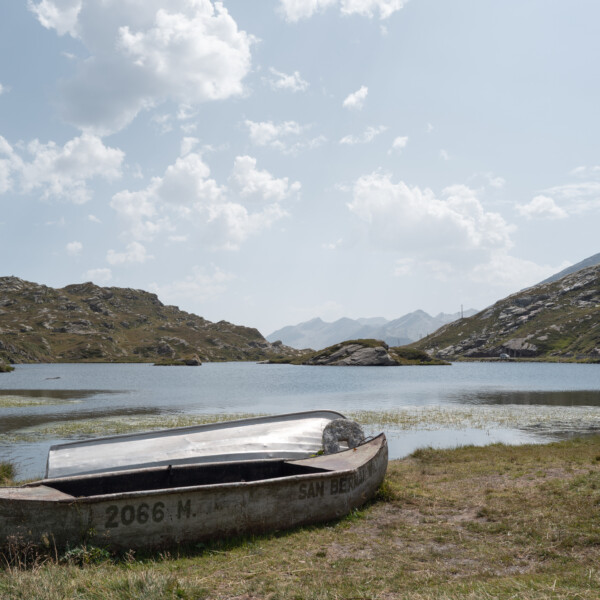 Laghetto Moesola: Zwei Boote am Ufer eines Bergsees mit Bergen im Hintergrund. 