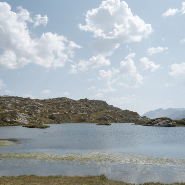 Rote Bank am Laghetto Moesola See in den Schweizer Alpen unter blauem Himmel.