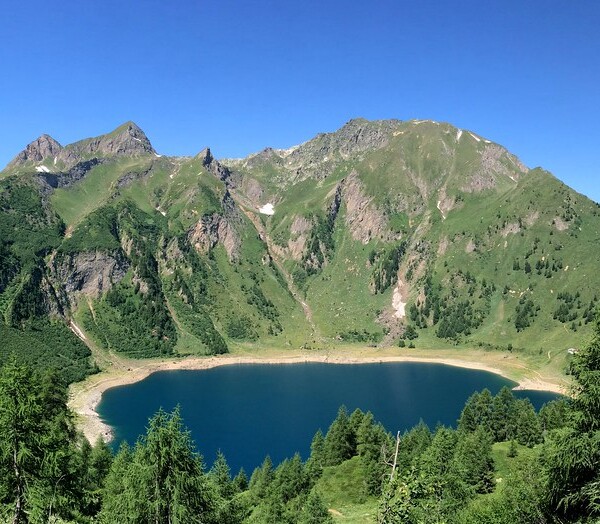 Lago Tremorgio, ein Bergsee umgeben von grünen Bergen und Wäldern in der Schweiz.