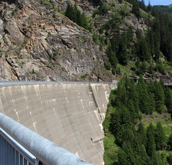 Lago del Sambuco Staumauer mit Berglandschaft und grünen Bäumen.