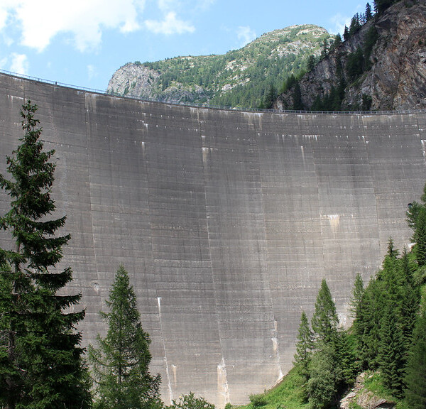 Lago del Sambuco Staumauer: Beeindruckende Betonstruktur in den Bergen, umgeben von grünen Bäumen.