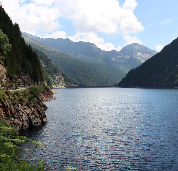 Lago del Sambuco: Blauer See umgeben von grünen Bergen und einer Straße.