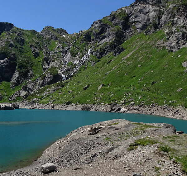 Lago del Zött: Türkisblauer Bergsee mit Wasserfall und grünen Hängen.