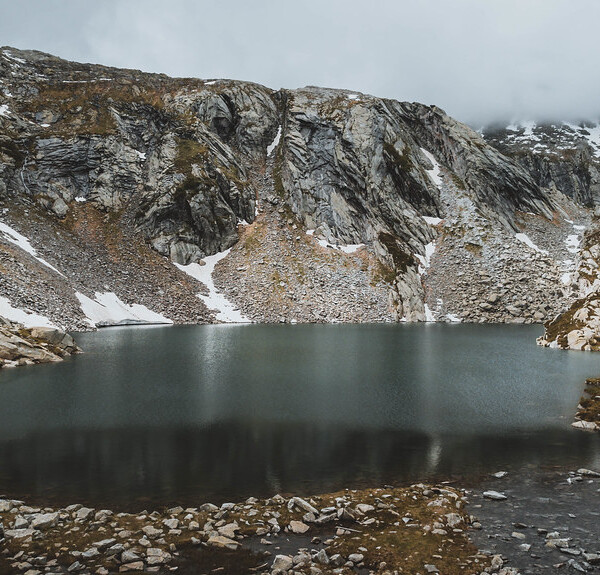 Lago di Sassolo, ein Bergsee umgeben von Felsen und Schnee.